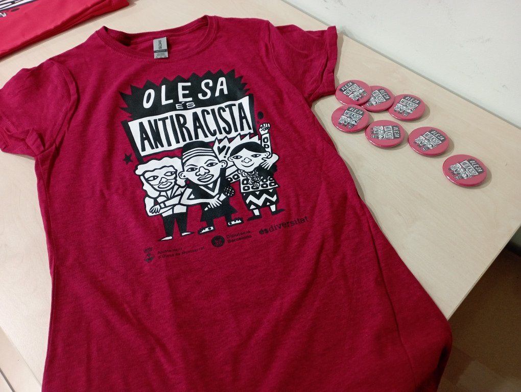 Samarretes i xapes amb l'eslògan "Olesa és antiracista"