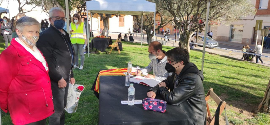 Parada de signatura de llibres amb dues persones esperant el llibre